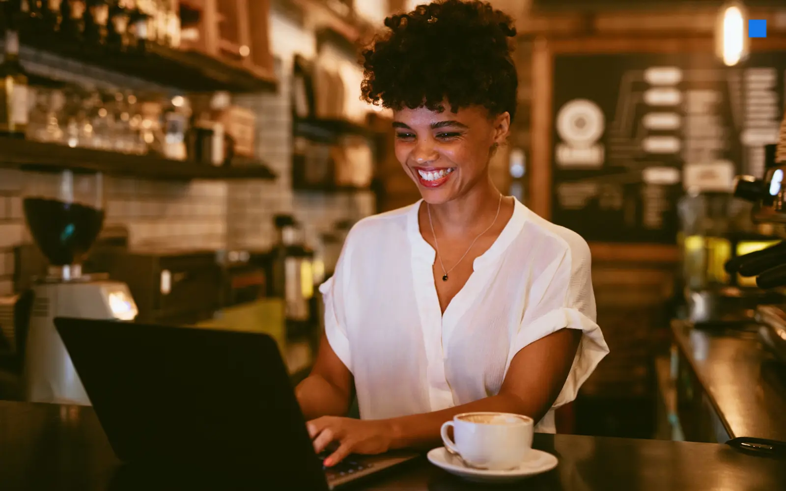 Smiling café owner working on a laptop at her counter